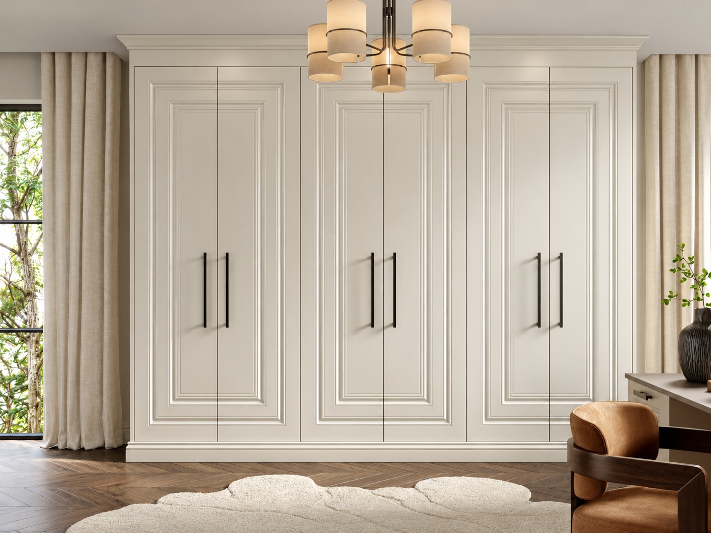 Full-height cream fitted wardrobes with panelled doors and long black handles in a bright room