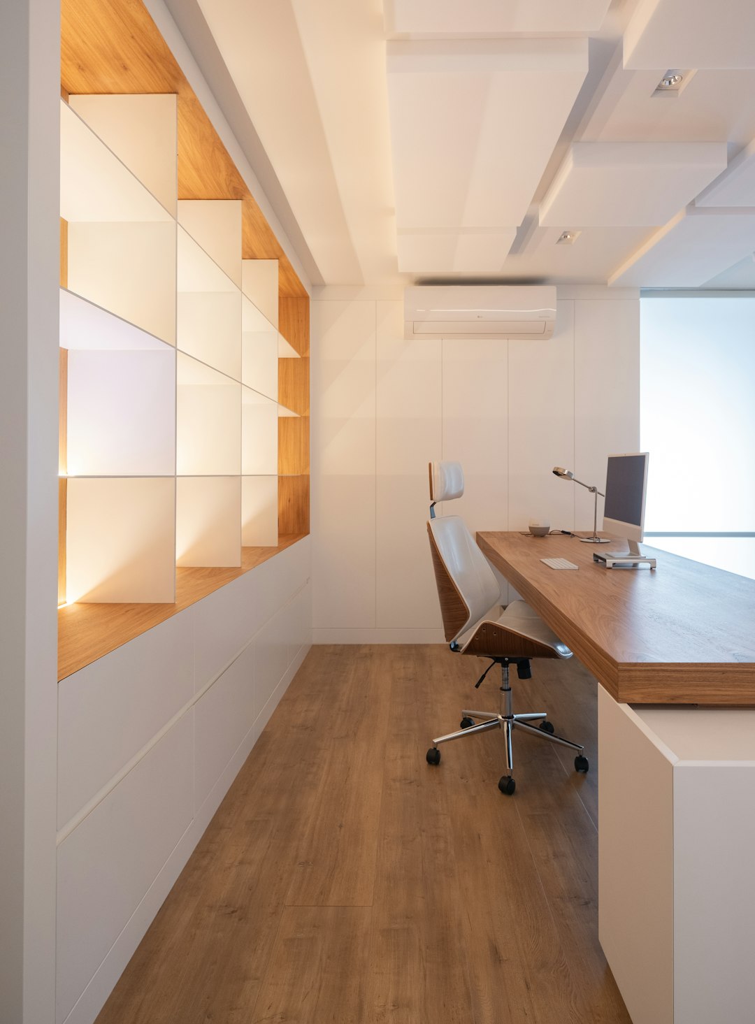 Bright office with an oak desk, fitted white cupboards and open shelving — inspiration photograph by Caroline Badran